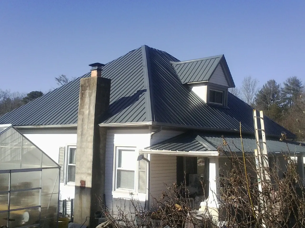 Dark blue standing seam metal roof on a white farmhouse with dormer — Slate & Tile Roof Repair by Roofing Brothers in Grand Coulee
