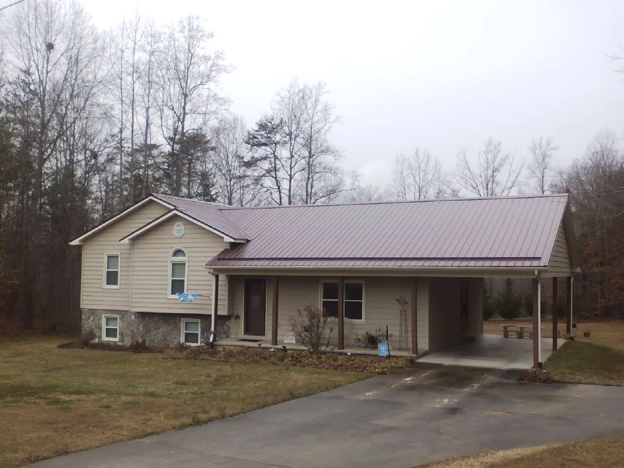 Burgundy metal roof on a tan split level home with an attached carport in Grand Coulee
