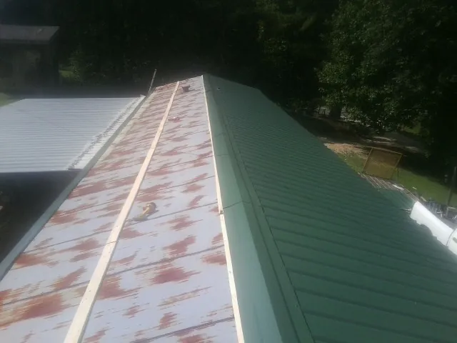 Old rusted panels beside newly installed green metal roofing — Wind Damage Roof Repair by Roofing Brothers in Grand Coulee