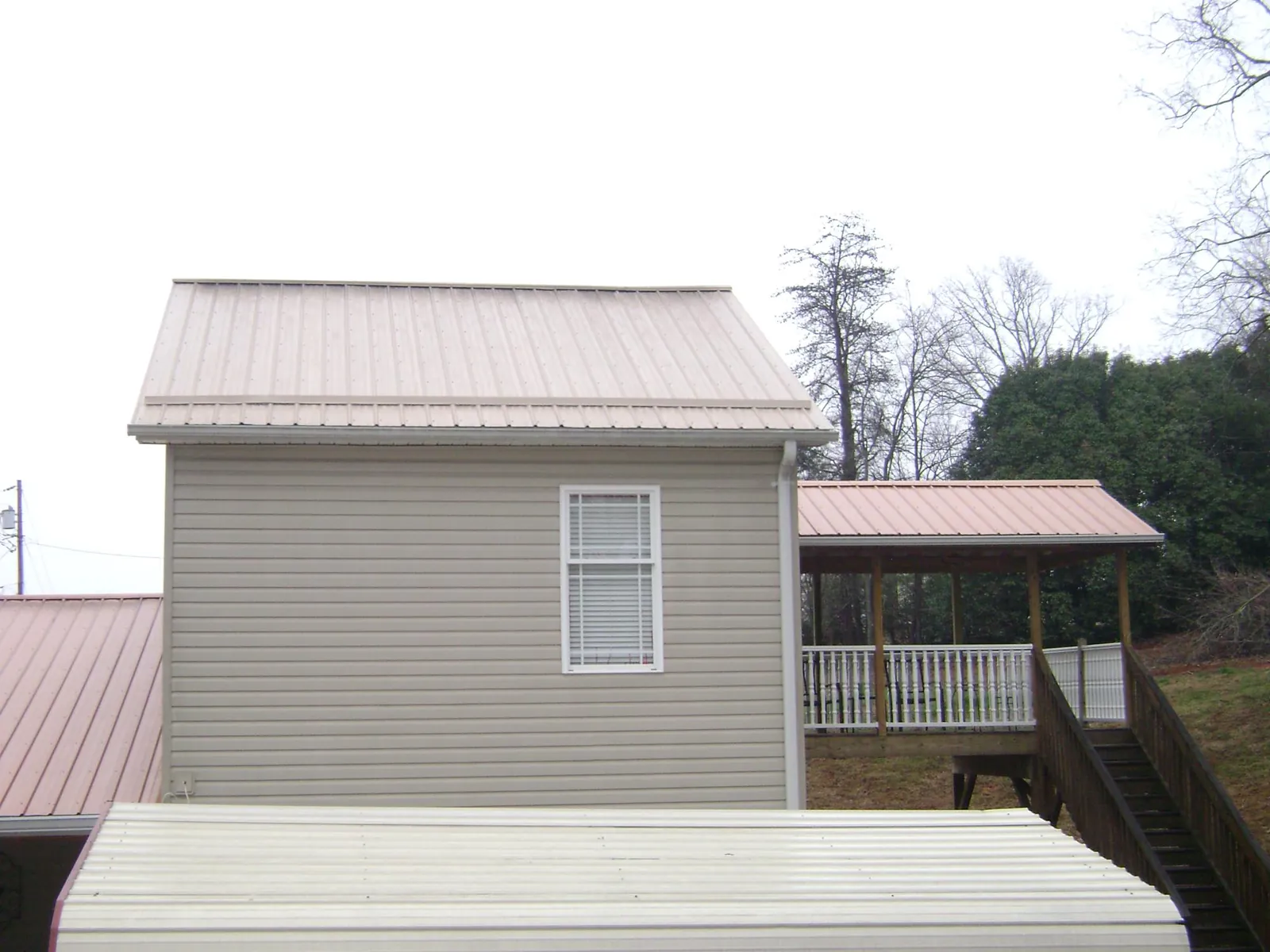 Tan metal roofs on a two story addition and attached porch, from a Roof Replacement job in Grand Coulee