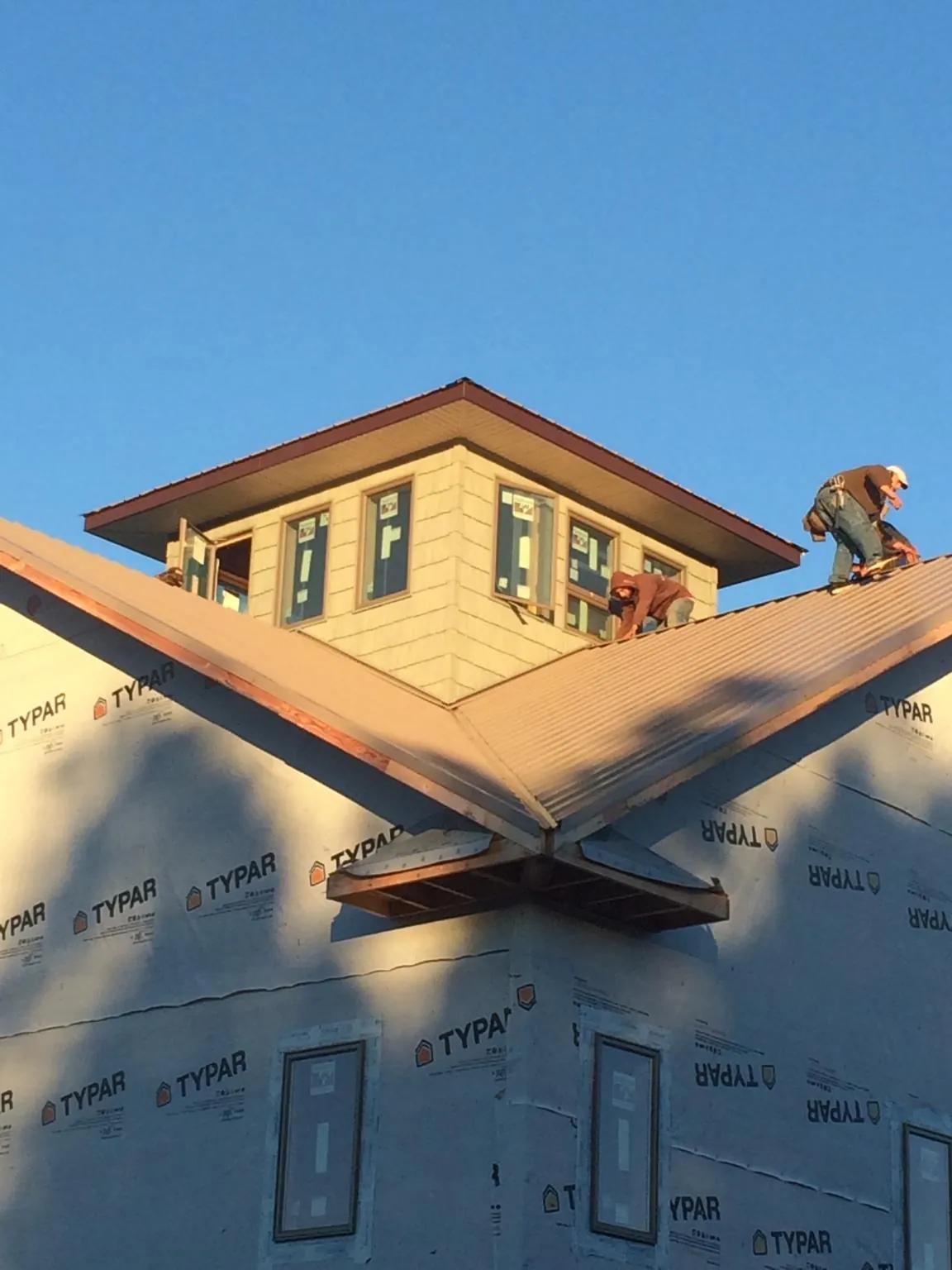 Roofers working around a rooftop cupola on a new metal roof at sunset — Roof Waterproofing in Grand Coulee by Roofing Brothers